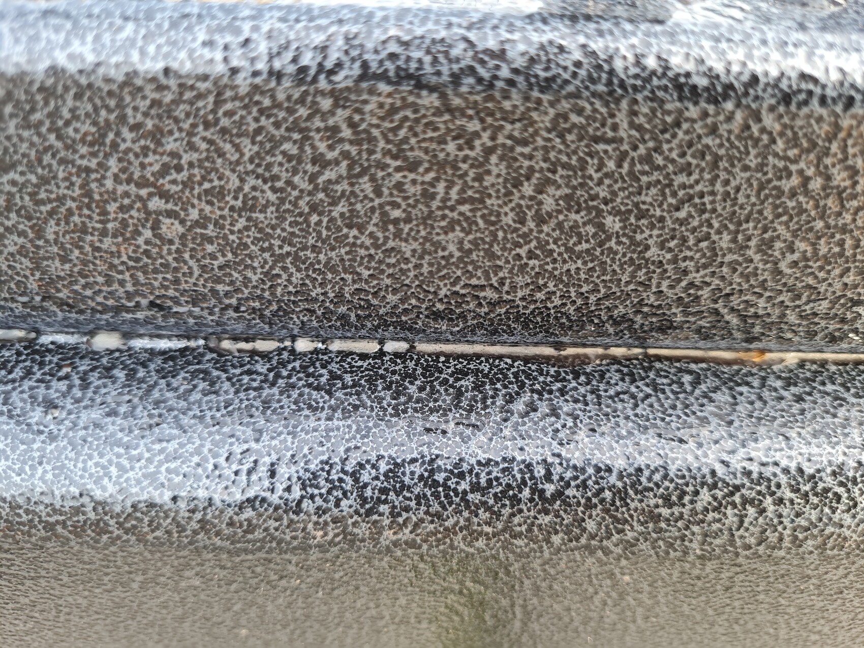 Close-up of a black leather surface with a grainy texture and horizontal seam.