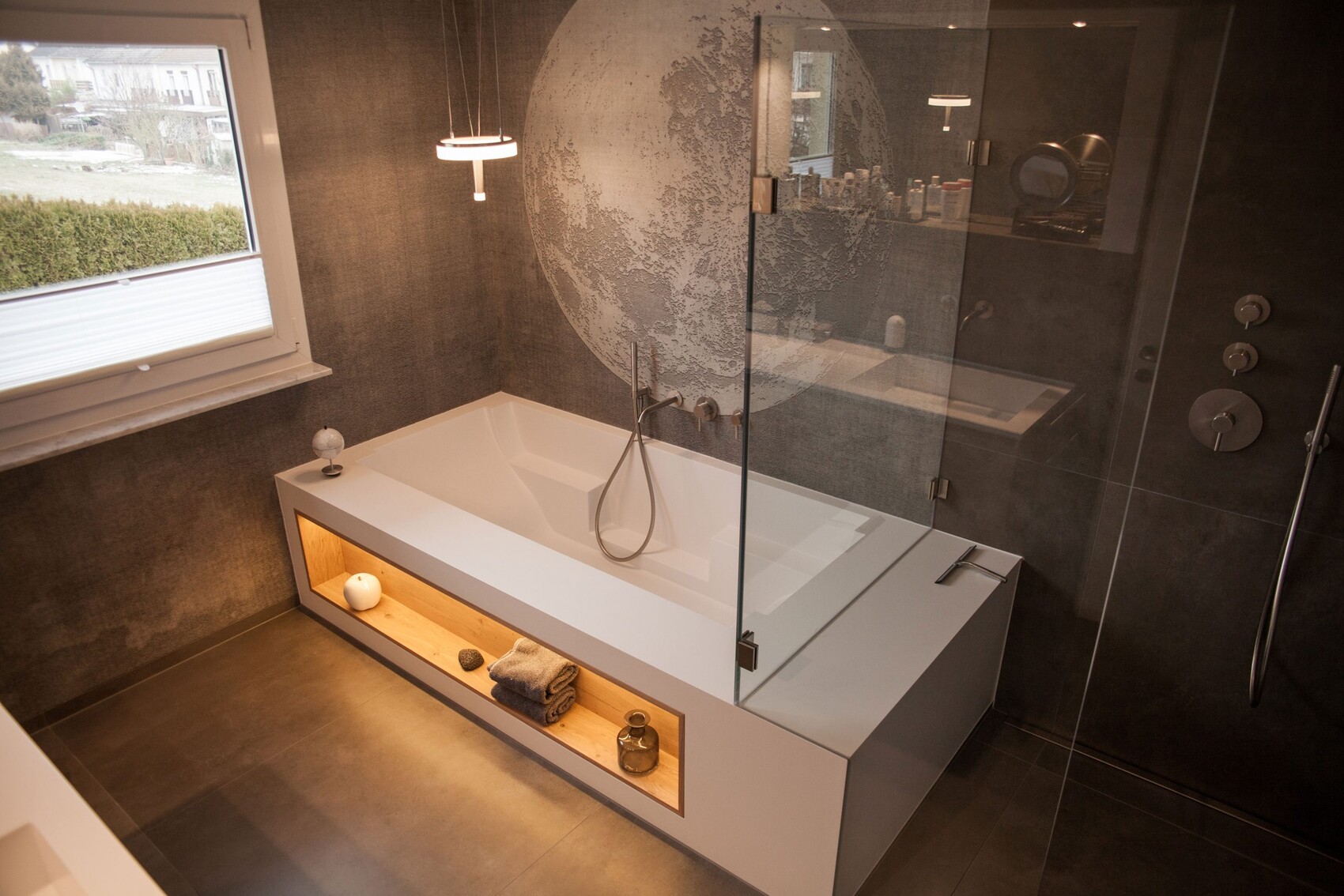 Modern bathroom with white bathtub, glass shower and dark tiles