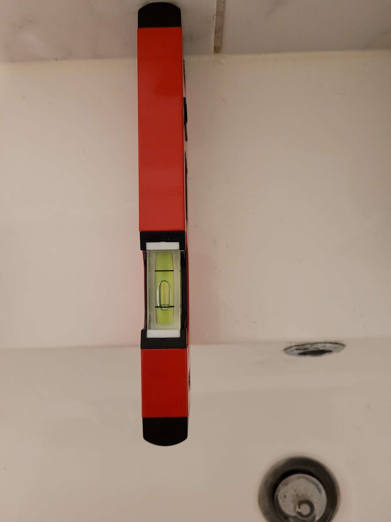 Red spirit level with green bubble window in bathroom