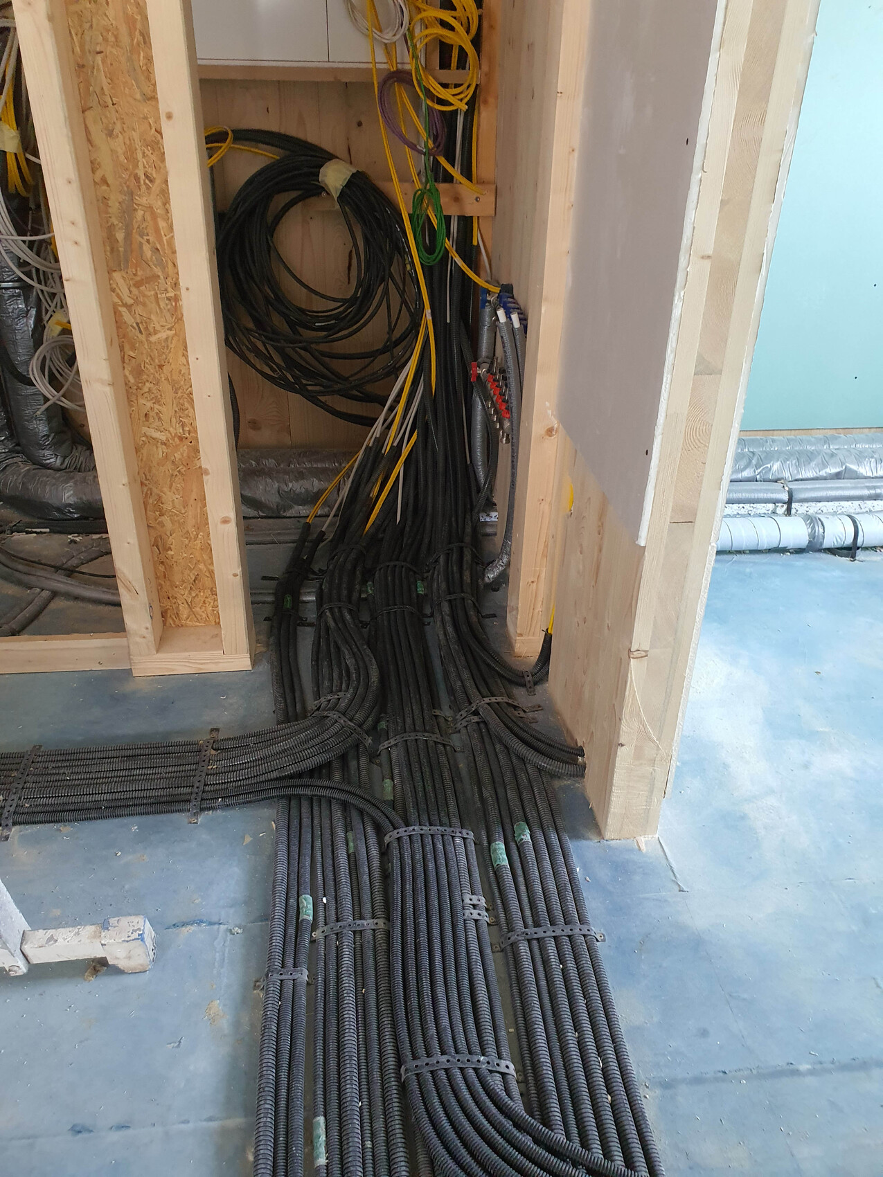 Construction site with many black cable bundles on the floor and within the wall structure.