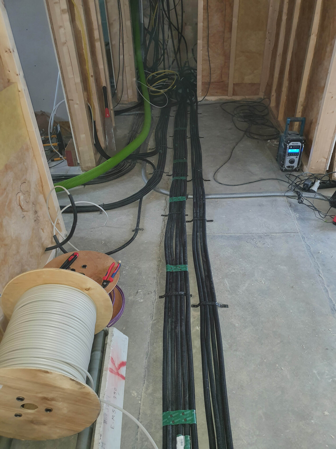 Shell construction site: Several black cable bundles lying on the floor, reels and measuring device visible.