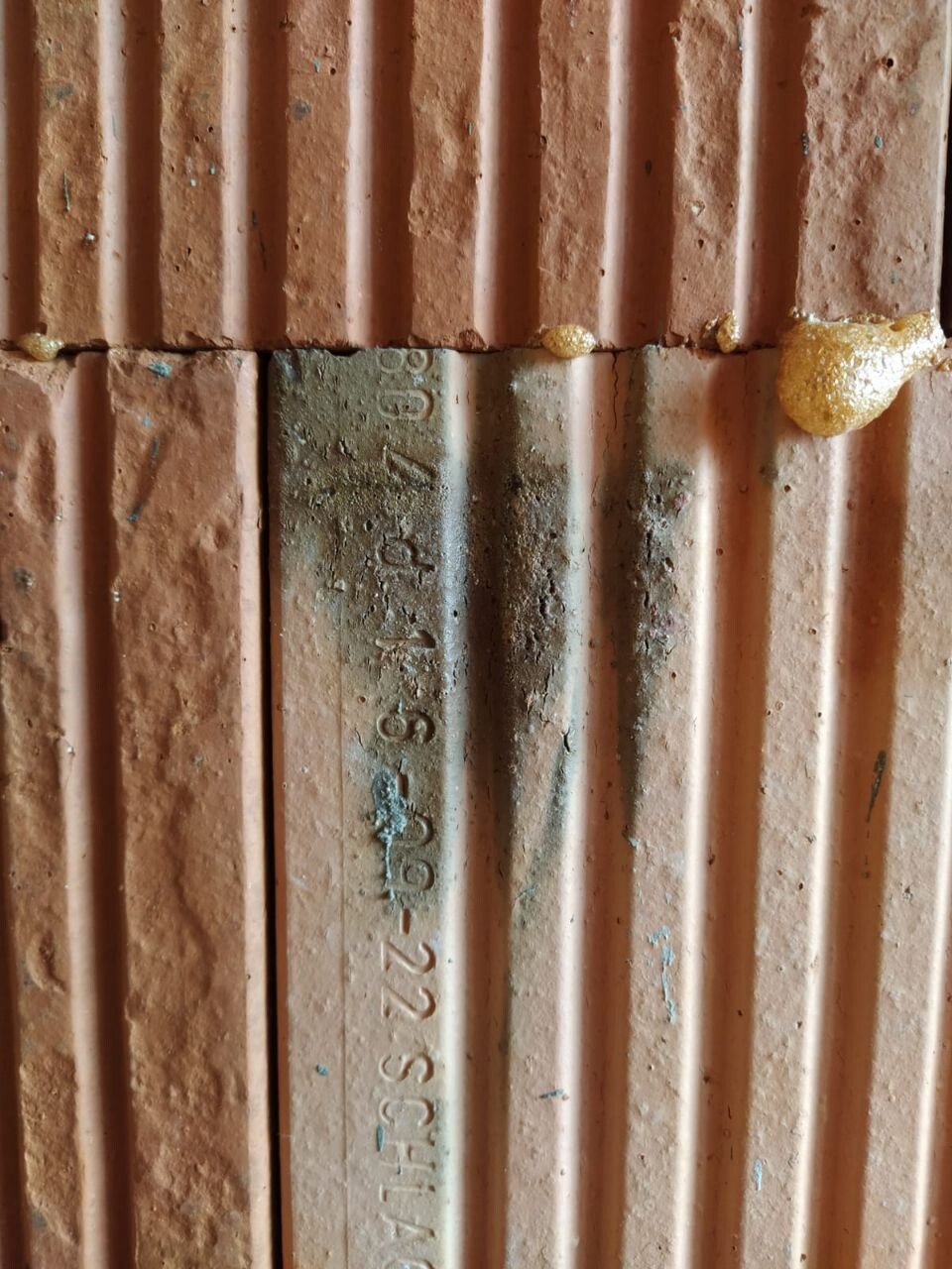 Rust-orange vertical ribbed panels; gray stripe in the center with numbered stamp.