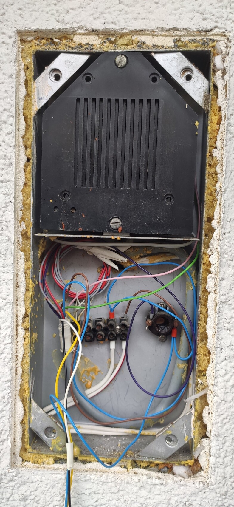 Open wall box with many colorful cables and a black electronic module.