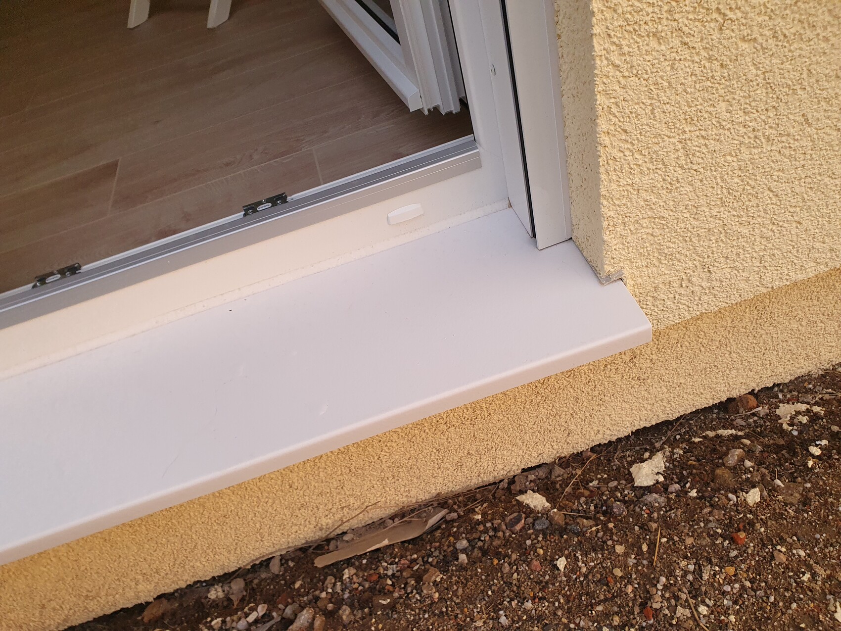Sliding door entrance: white threshold, beige exterior wall, interior floor wood look