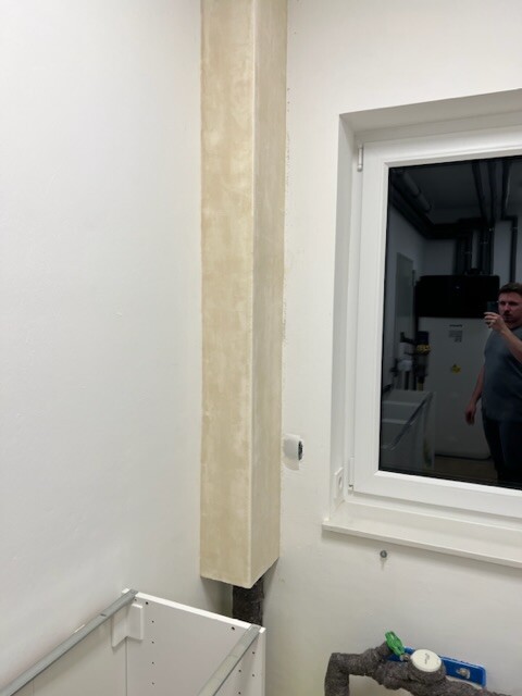 White interior with a column; window reflects a man.