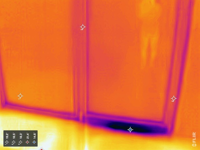 Thermography of an interior with door frame; faint outline of a person is visible at the top right.