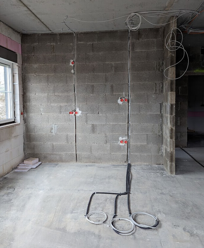 Shell construction: Unplastered brick wall, exposed wiring, red sockets, cables on the floor.