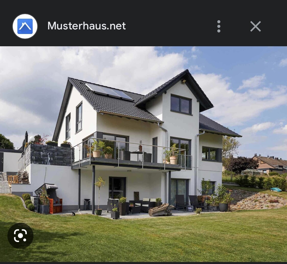 Modern two-story house with balcony, terrace, garden plants, and solar panels on the roof.