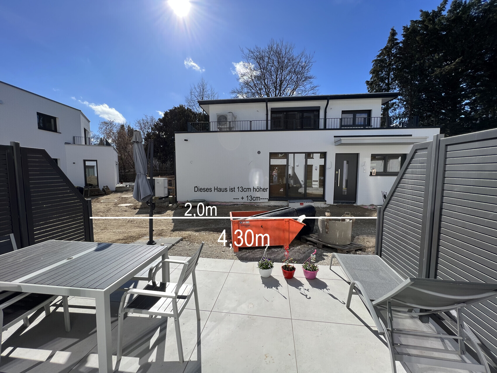 White modern house under construction, terrace with furniture; construction site, measurement lines 2.0 m and 4.3 m, sunny.