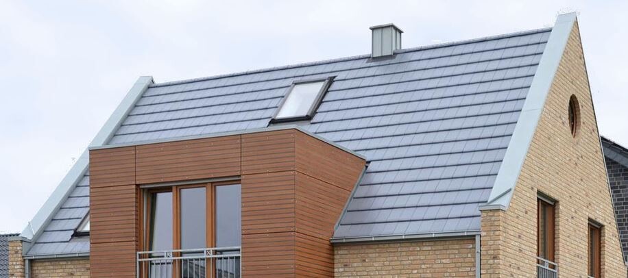 Außenansicht eines modernen Ziegelhauses mit Satteldach, Dachfenster und Balkon.