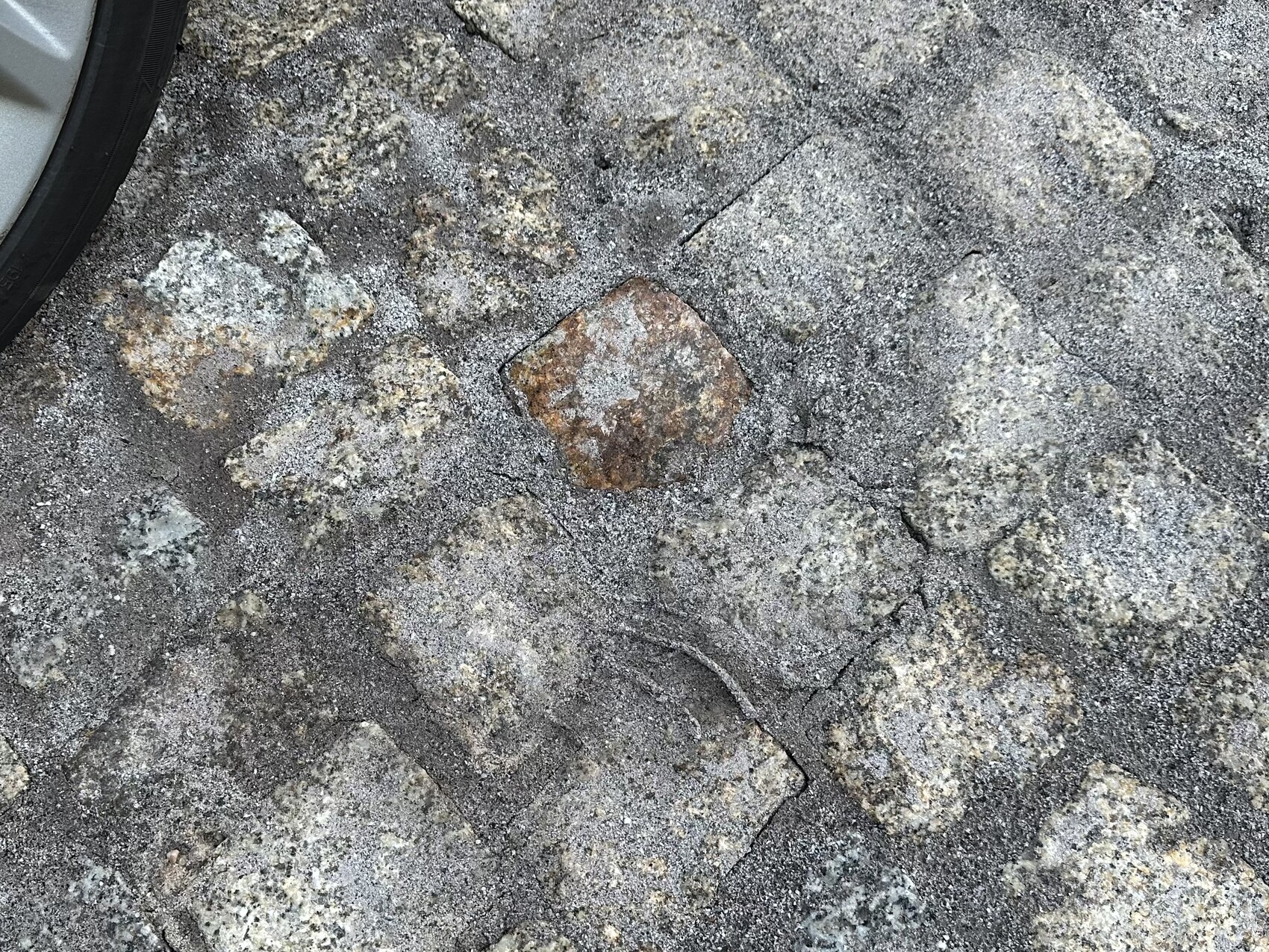 Close-up of stone paving with grey/brown stones; red stone in center.