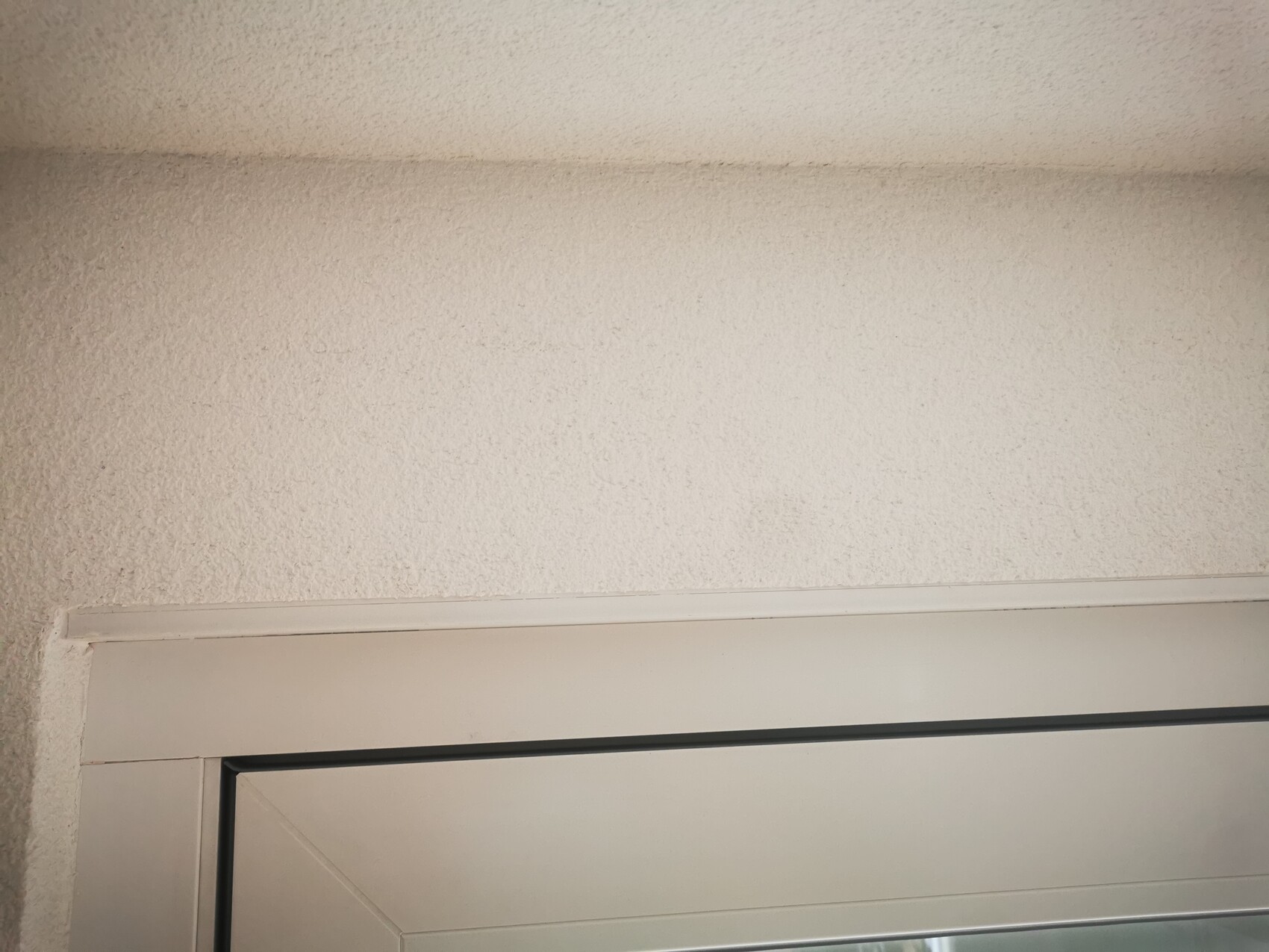 White door frame at the bottom of the image in front of a roughly textured white wall.