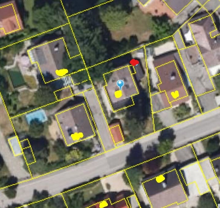 Aerial photo of a residential area with yellow property boundaries, blue location pin, and markers.