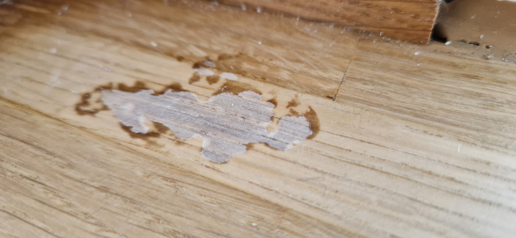 Wood flooring with damaged surface coating; exposed light wood in the center.