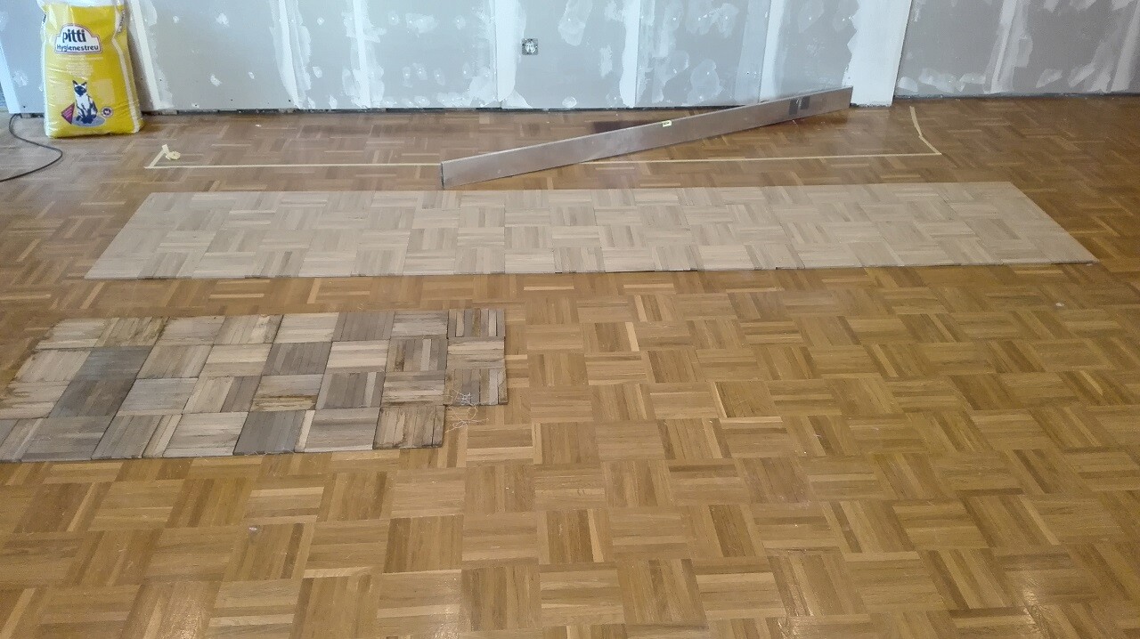 Living room floor with laid parquet and building materials in the background.
