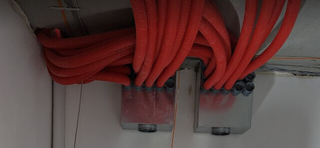 Bundles of red cables lead to two silver metal distribution boxes on the ceiling.