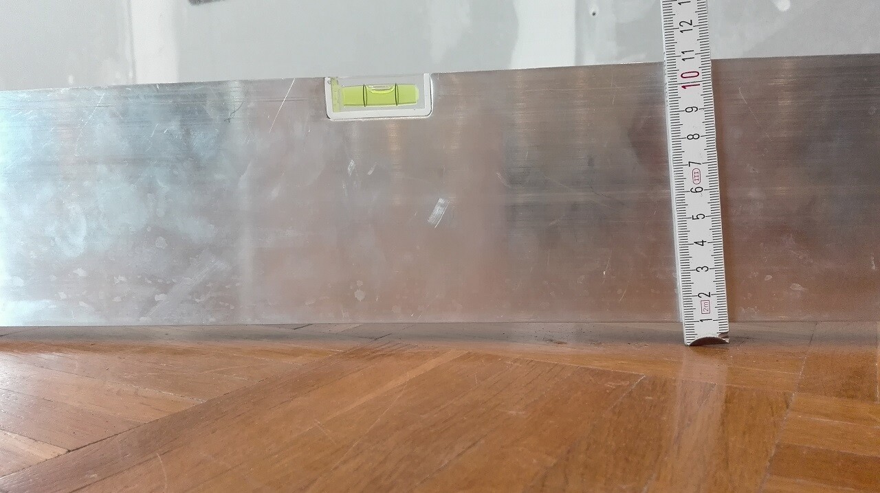 Close-up of a shiny metal cladding with a spirit level and measuring tape in interior finishing