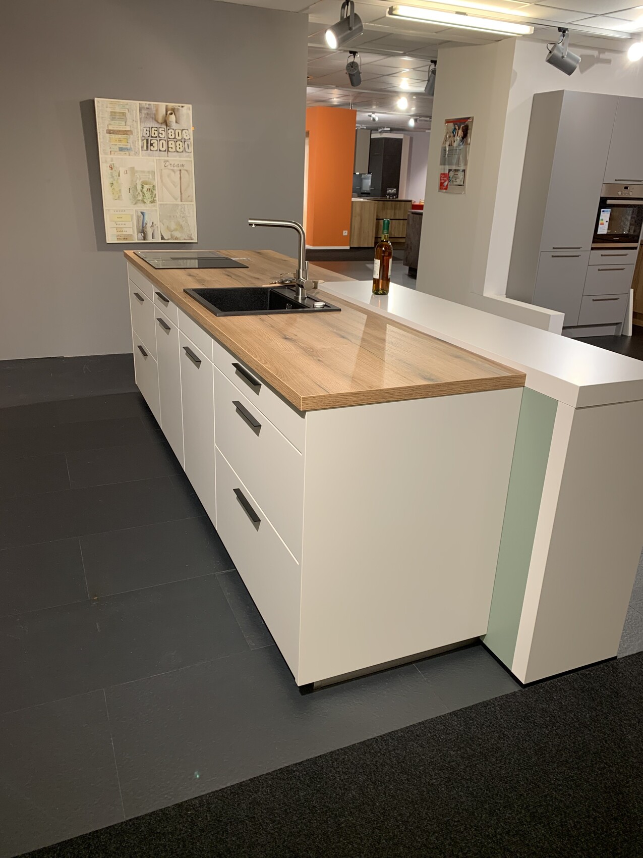 Modern kitchen island with wooden countertop, sink, faucet, and white cabinets in showroom.