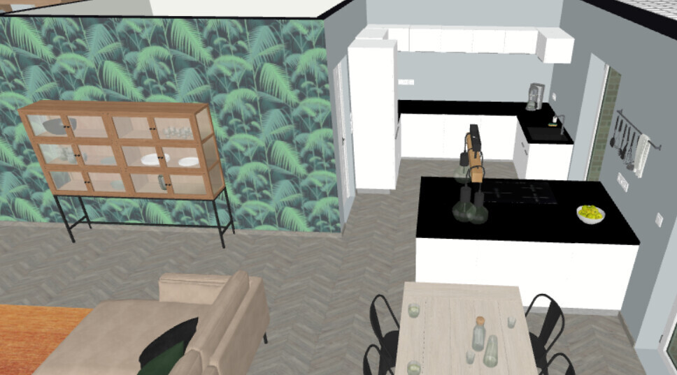 Open kitchen with black island, dining table and palm wallpaper; person at kitchen island.