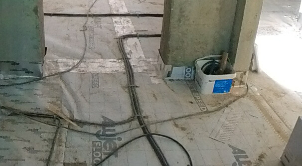 Construction site: floor with laid black cables, green supports, bucket and toolbox