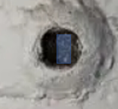 Drill hole in concrete shell with rough surface and dark hole.