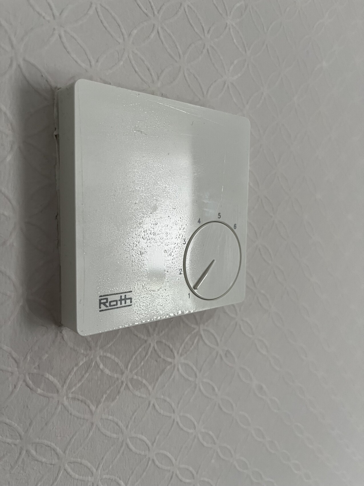 White wall thermostat with round knob, scale 0-6 and Roth logo.