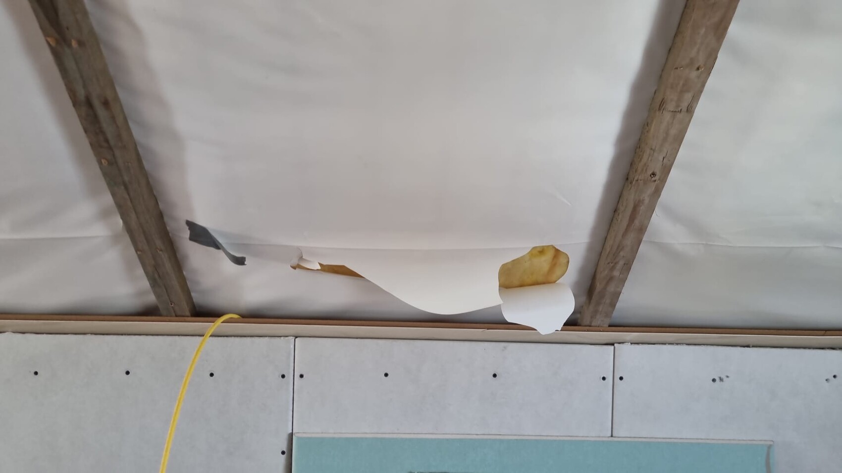 Construction site with exposed ceiling beams, drywall panels and cables in interior construction