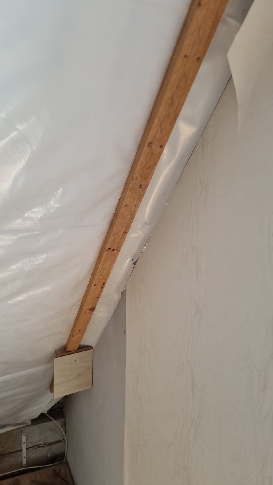 Attic with wooden beams, white plastic waterproofing and roof cladding