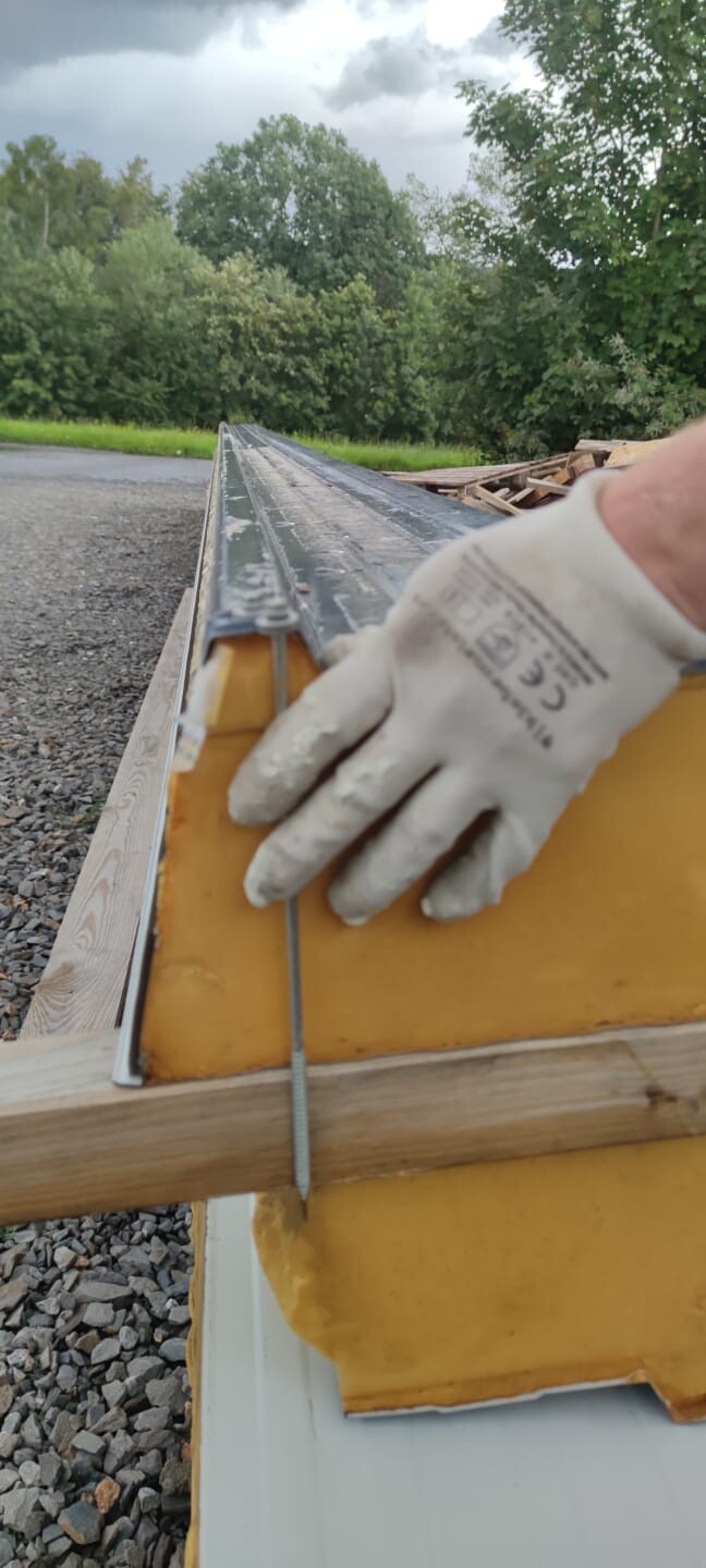 Hand in work gloves fastening wire to yellow building form on construction site