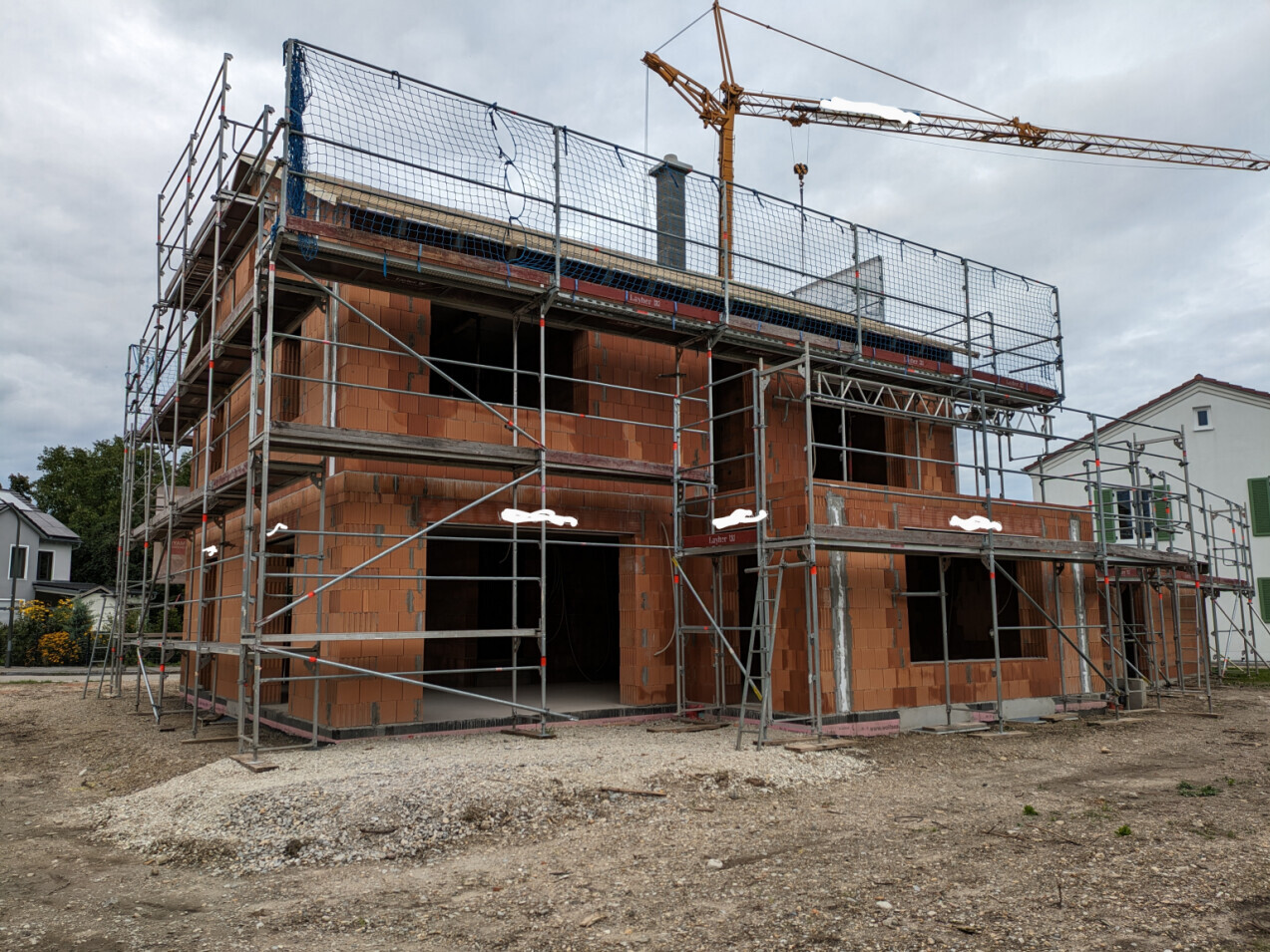 Shell construction of a multi-story building with scaffolding and crane in the background