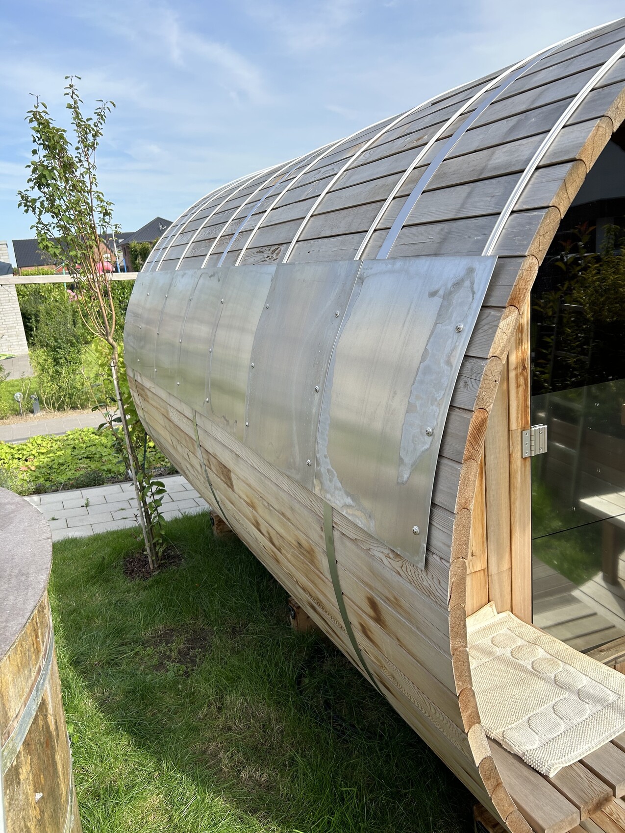 Garten-Holz-Pod mit gewölbtem Dach aus Holz, seitliche Metallplatten, Glasfront.