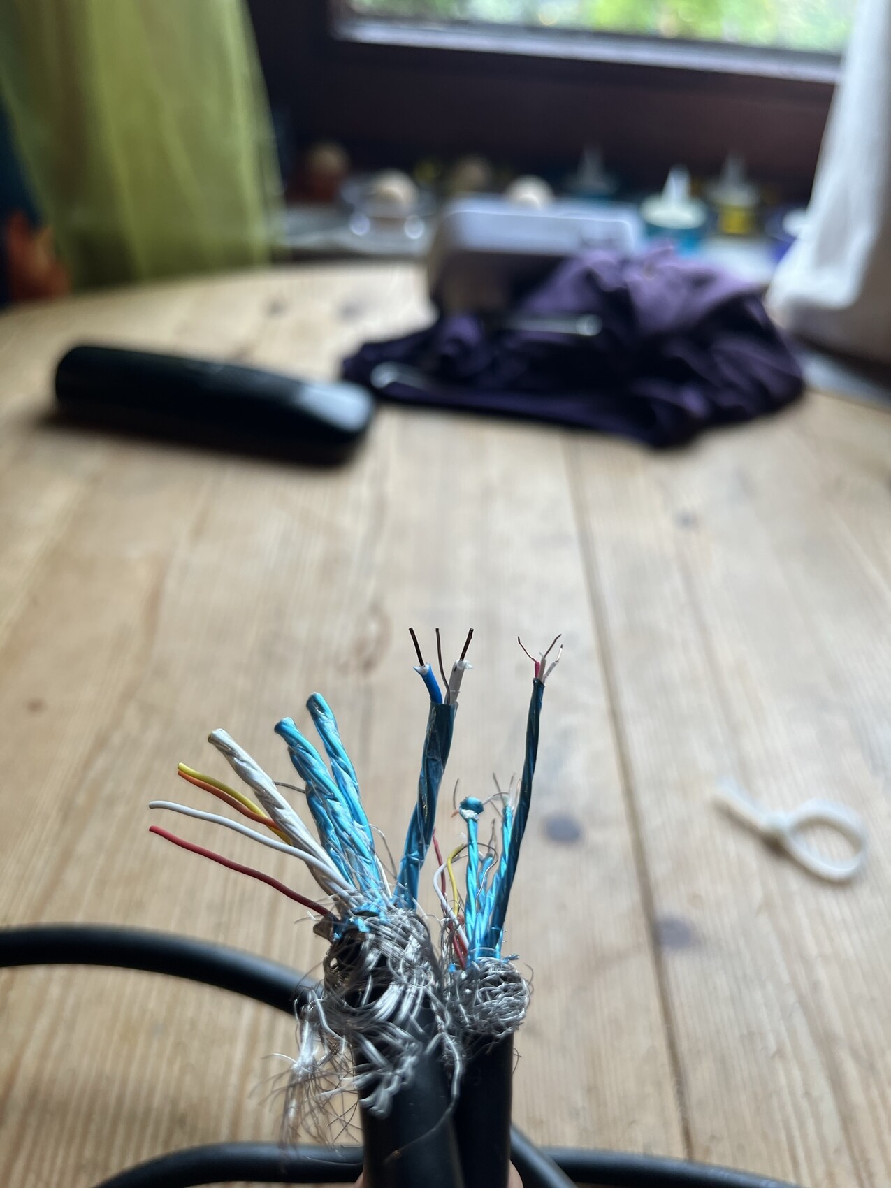 Cut network cables with colored wires on a wooden table, blurry background.