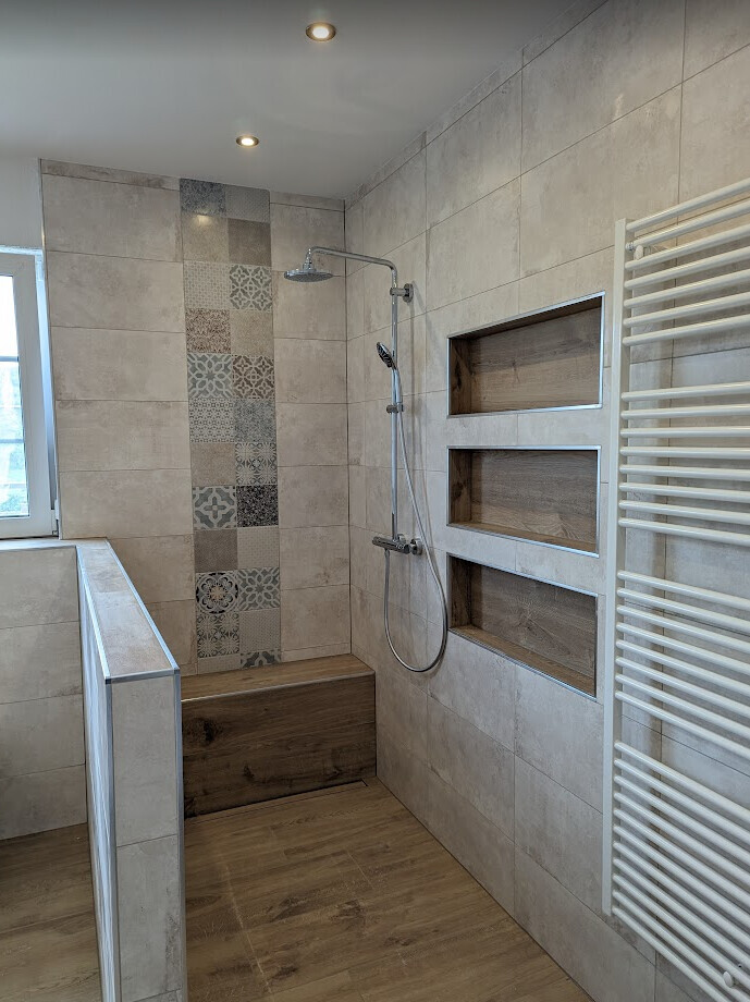 Modern bathroom with beige tiles, shower, wooden bench and towel radiator.