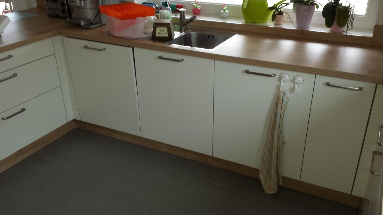 Kitchen with white base cabinets, wood countertop, sink, window sill with plants; towels hanging.