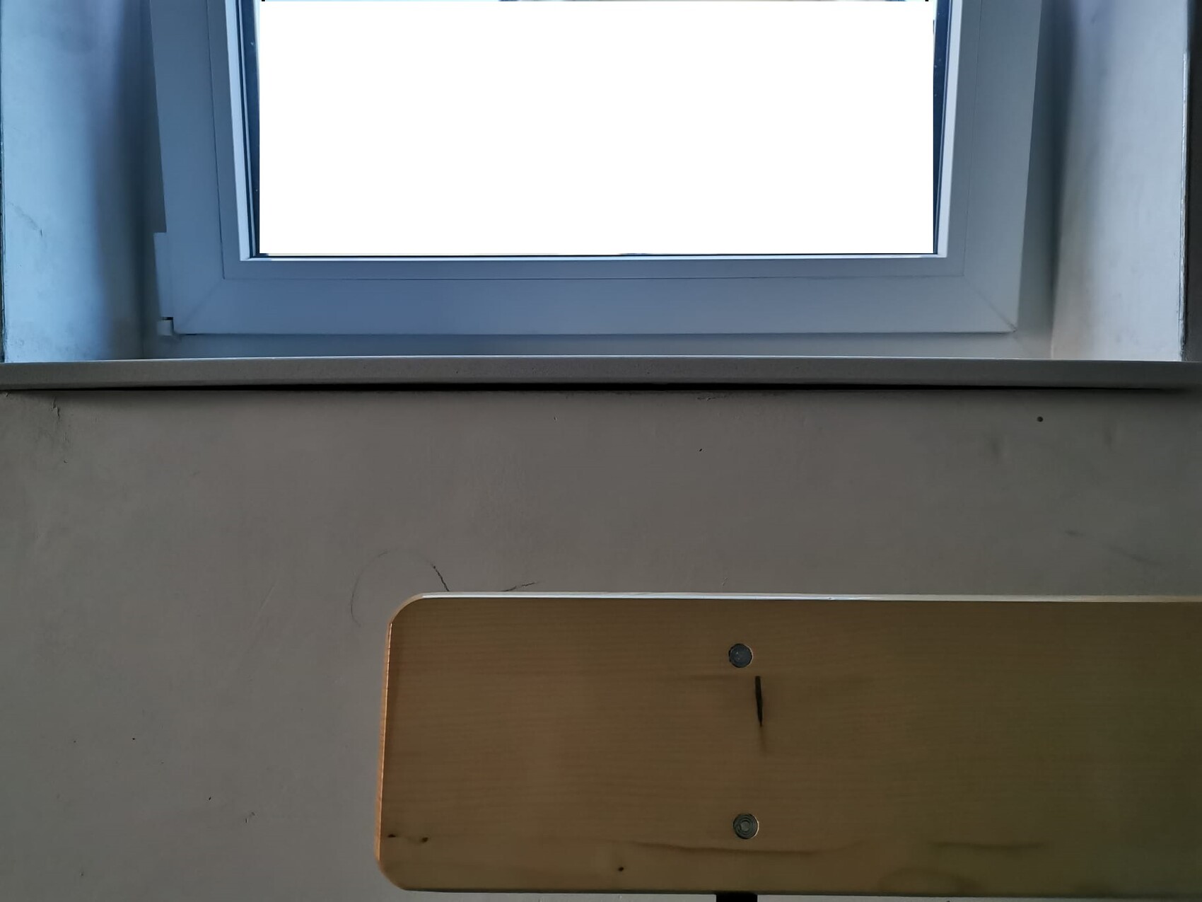 Interior: wooden bench at bottom right against gray wall, large window above.