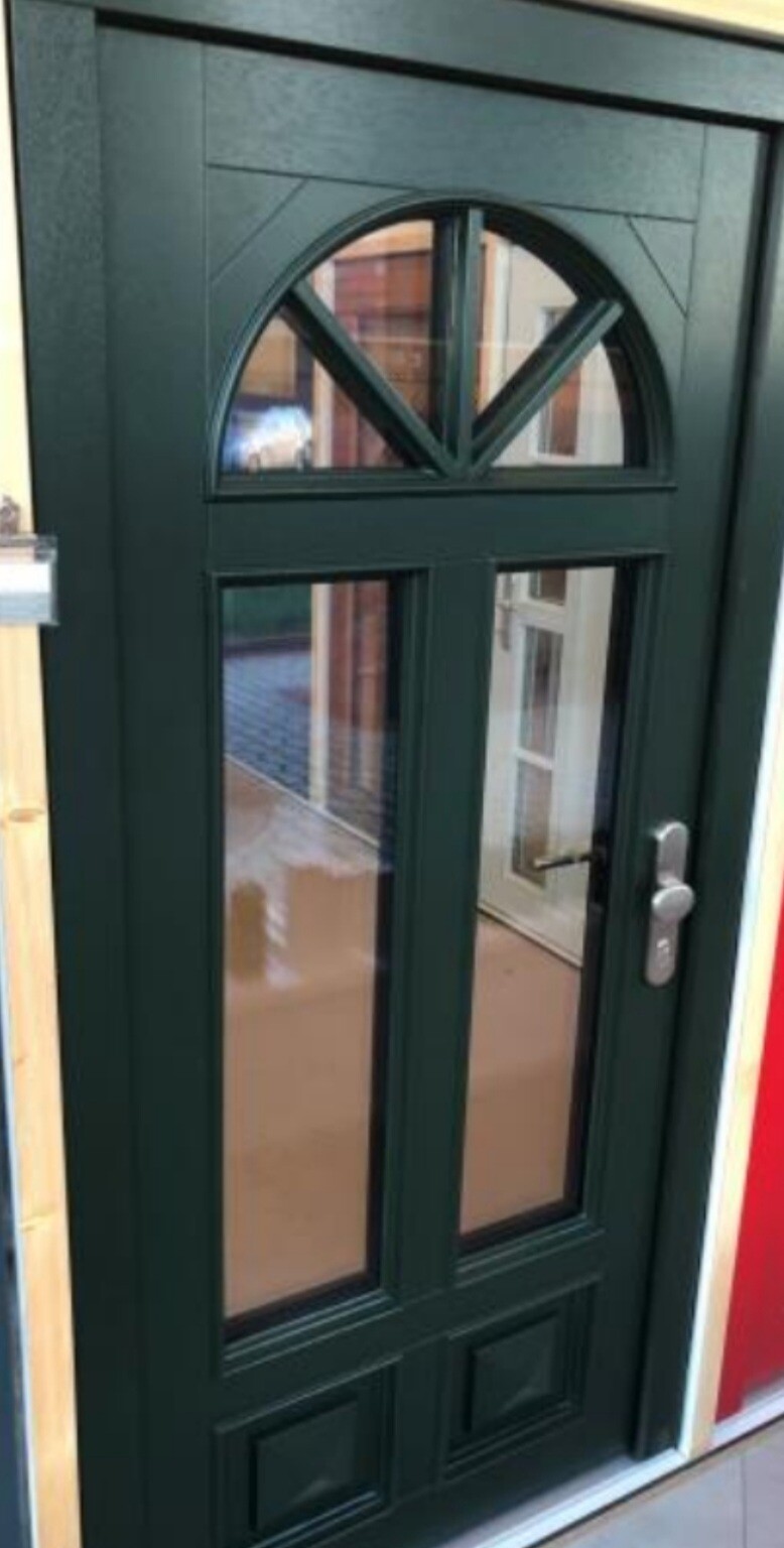 Dark green front door with glass windows, rounded transom, and handle on the right.