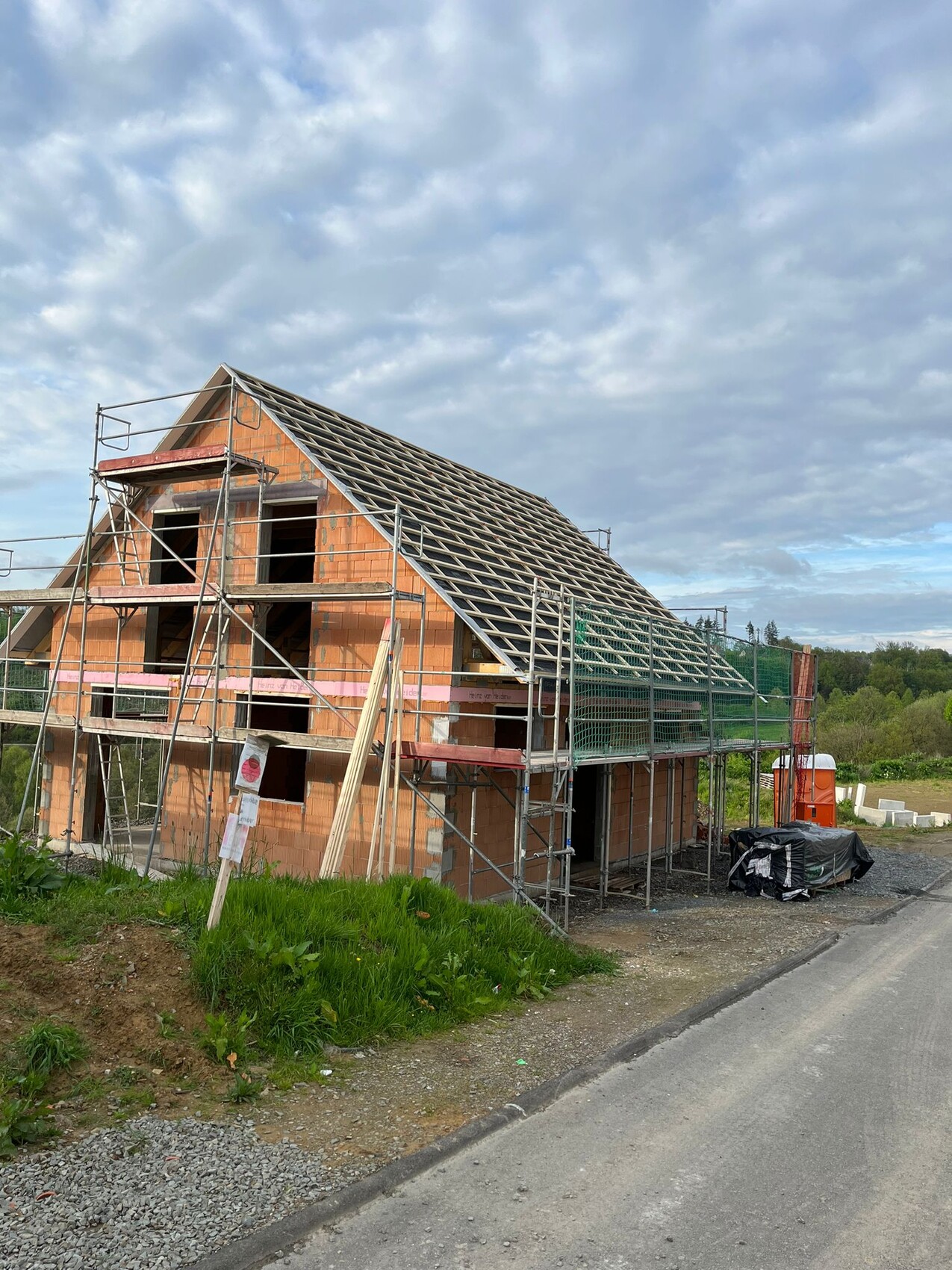 House under construction with scaffolding, brick walls, and roof structure
