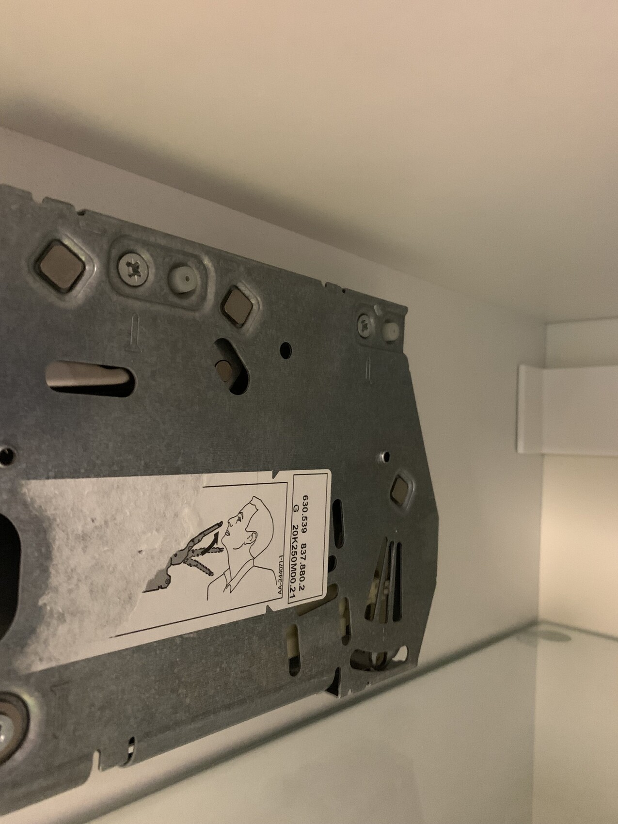 Metal mounting rail with screws and sticker, presumably the back of a device.