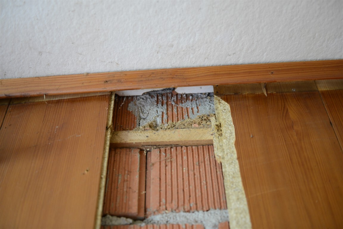 Freiliegter Ziegelbodenbereich zwischen Holzdielen, sichtbar Baumangel und Mörtelreste