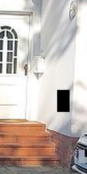 White house front with wooden steps, door with rounded window, outdoor light.