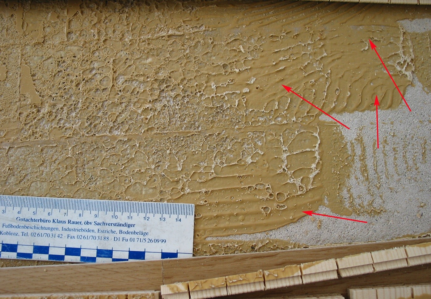 Close-up of a wall surface with wet plaster, uneven texture, measuring rod visible