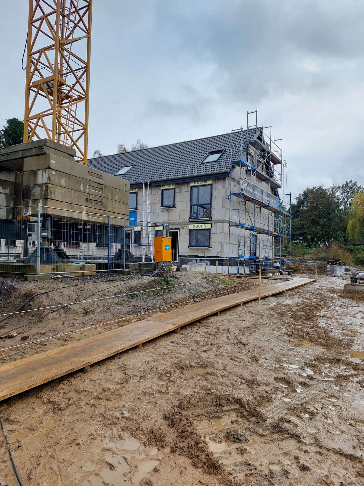 Construction site with shell, crane, scaffolding and building plot at the new house construction