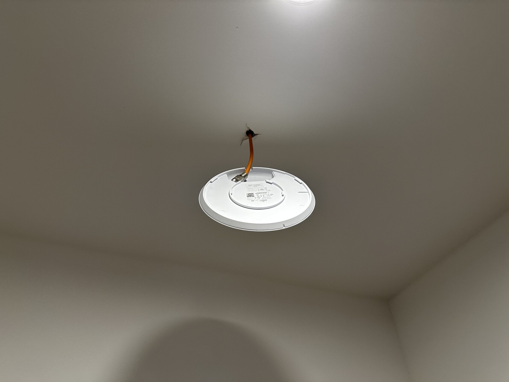 Hanging round ceiling light with orange cable, not yet installed.