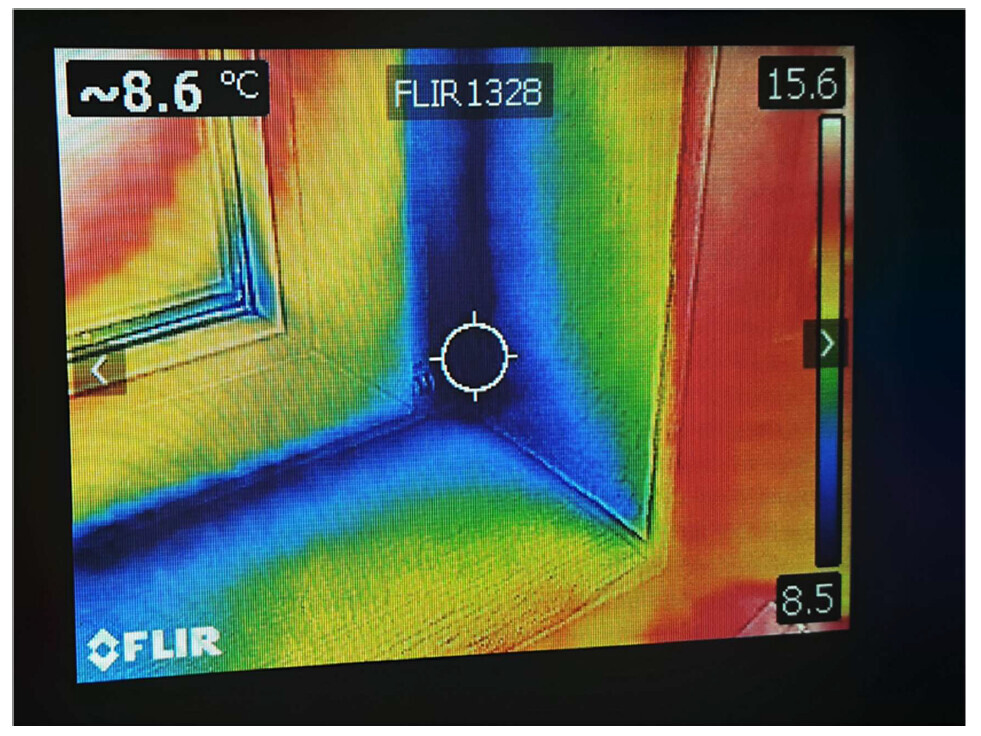 Thermografische Aufnahme einer Fenster-Ecke; blaue Kältezone, warme Wand, Zentrum markiert.
