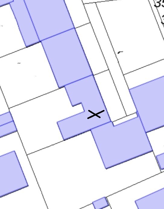 Site plan with white buildings, purple marked areas, and a black X as location indicator.