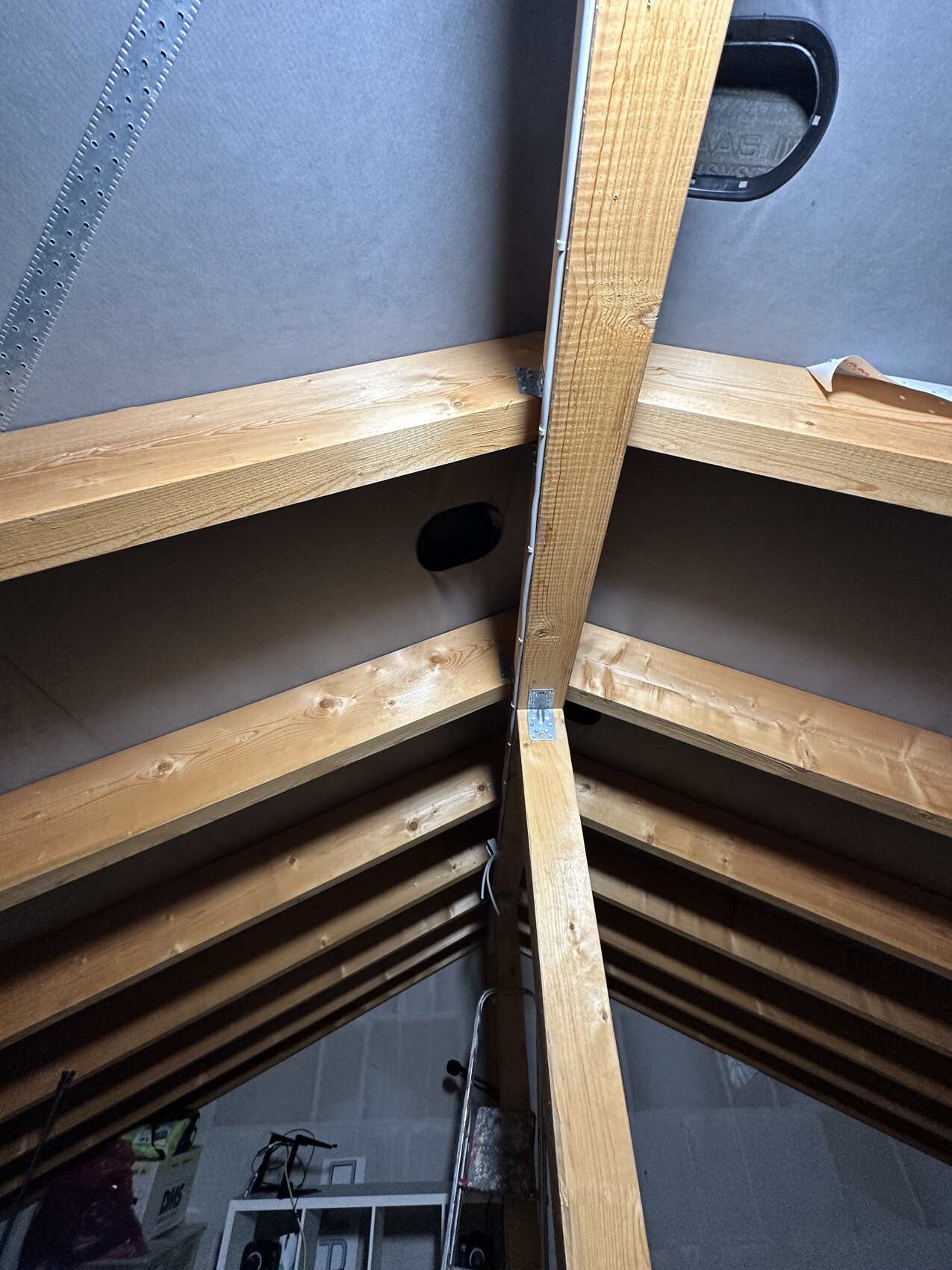 Attic with wooden rafters, central beam, and metal angle connectors