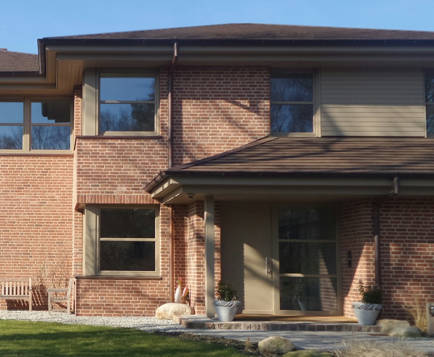 Two-story brick house with front door, large windows, gravel path and planter boxes