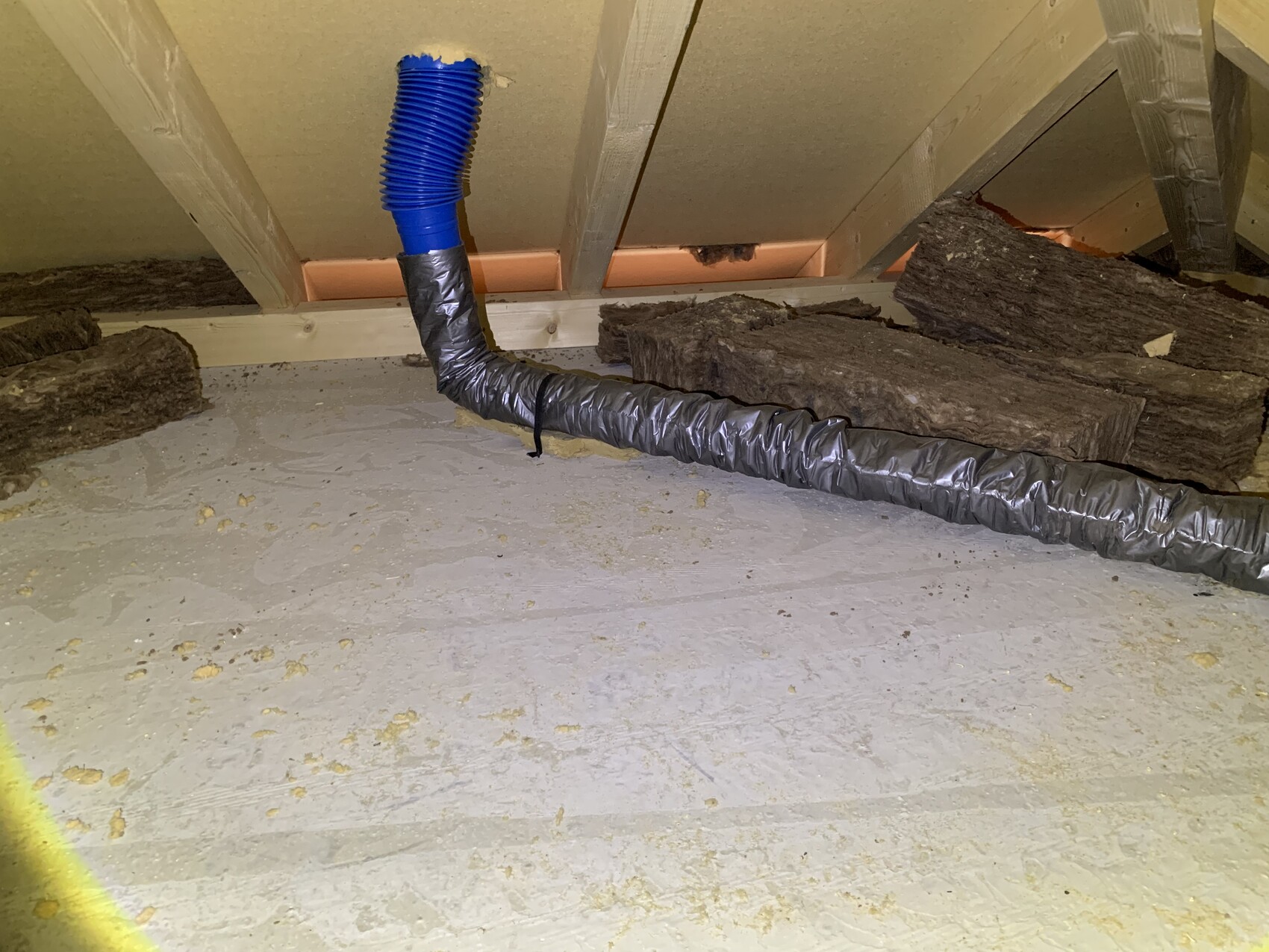 Attic: blue flexible hose connects to silver insulation, wooden beams visible.
