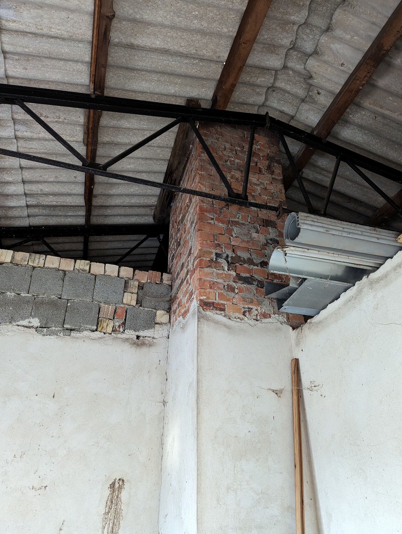 Interior of an unfinished building with exposed brick wall, steel beams, and concrete blocks.