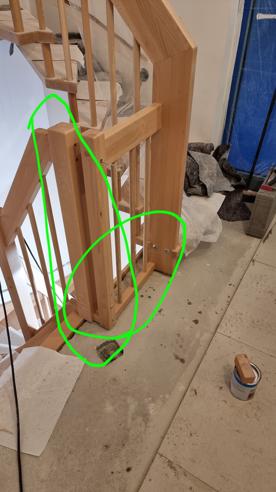 Wooden staircase with railing under construction, hole in the floor next to a paint can.